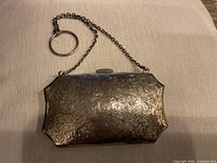 Front view of engraved sterling silver purse with chain and finger ring