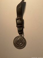 Full view of medallion with attached leather strap and buckle