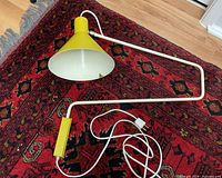 Lamp overall view on rug showing yellow cone shade and white elbow arm