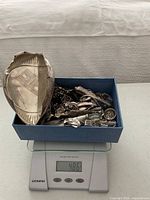Box of assorted scrap silver on scale displaying 486 g