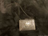 Front view of engraved sterling silver dance purse showing chain handle and monogram cartouche