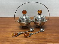 Front view of twin sterling dishes with amber finials and spoons