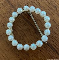 Front view of circular gold brooch with pearls