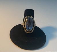 Front view of 14K gold ring displaying oval blue stone and scalloped setting