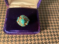 Front view of gold ring with turquoise stones in presentation box