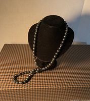 Necklace displayed draped on black bust