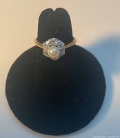 Ring front view on stand showing pearl and diamond halo