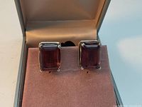 Front view of both earrings showing red stones and silver prongs