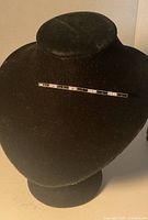 Brooch displayed on black stand showing full length