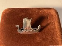 Front view of silver Viking ship brooch on display pad