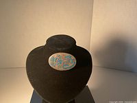 Full view of oval silver brooch on display stand