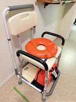 Overall view of shower chair with cushion, first-aid kit and scale