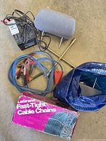 Group shot showing battery charger, lug wrench, jumper cables, headrest, tire chain box and bag