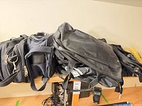 Three black nylon bags stacked on a table