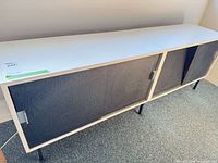 Full view of white credenza with grey sliding doors and black legs