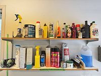 Two shelves of assorted cleaners, automotive fluids, aerosols