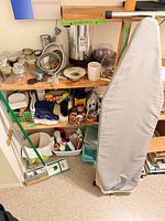 overall shelving view with ironing board, mop, jars, utensils, iron and cleaning supplies