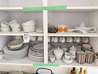 Cabinet view showing plates, bowls, ramekins, citrus cups and juicer