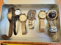Tray view of six wristwatches showing overall mix of styles and straps