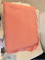 Peach blanket atop beige textured blanket