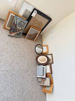 Grouping of all frames stacked against wall on carpet