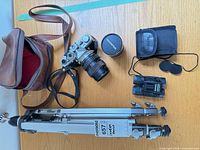 Group shot of all items: camera with lens, extra lens in case, binoculars with pouch, tripod, camera bag