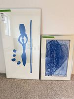 Both framed prints leaning against wall