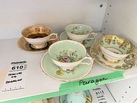 Four Paragon teacup and saucer sets on shelf