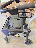 Close view of rollator showing seat, basket, handles and wheels