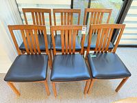 Front view of all six wood dining chairs showing slat backs and black seats