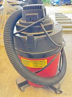 Full view of red canister shop vac with hose attached