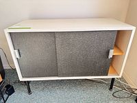 Front view of sideboard showing white frame, grey sliding doors, black legs
