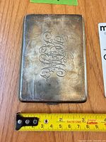 Front view of tarnished sterling silver cigarette case with monogram and measurement tape