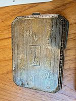 Front view of sterling silver compact showing stripe pattern and monogram