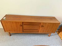 Front view of teak sideboard showing doors, drawers, legs