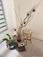 All four items together – twig arrangement in vase, ZZ plant with pot and saucer, mosaic-top side table, ceramic panel