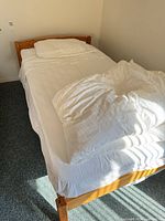 Full view of assembled twin bed with pine frame and white bedding