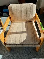 Front view of beige upholstered chair showing wood arms and cushions