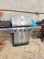 Front view of closed Char-Broil stainless steel 4-burner grill with side burner and cabinet