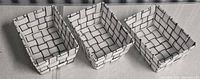 Three matching white and black woven plastic baskets