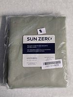 Front of sealed curtain package showing Sun Zero branding and attached size label