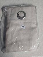 Panel inside sealed clear plastic showing folded fabric and grommet