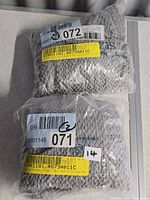Two sealed packages displaying barcodes and grey fabric