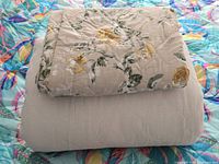 Folded quilt set showing floral face and striped reverse