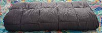 Rolled grey weighted blanket on patterned surface