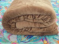 Rolled brown fleece blanket on patterned surface
