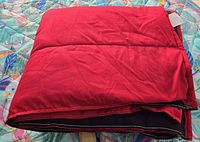 Folded red and black comforter on patterned surface
