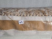 Rolled rug showing fringe detail in packaging