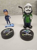 Group shot of figurine, bobblehead and two pucks