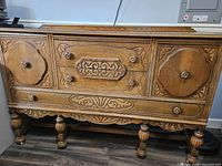 Full view of carved oak buffet showing doors, drawers, legs